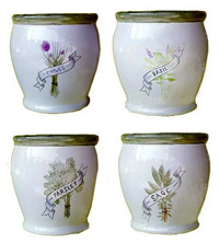 A selection of glazed ceramic pots with a herb designs forming a four piece herb set