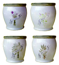 A selection of glazed ceramic pots with a herb designs forming a four piece herb set